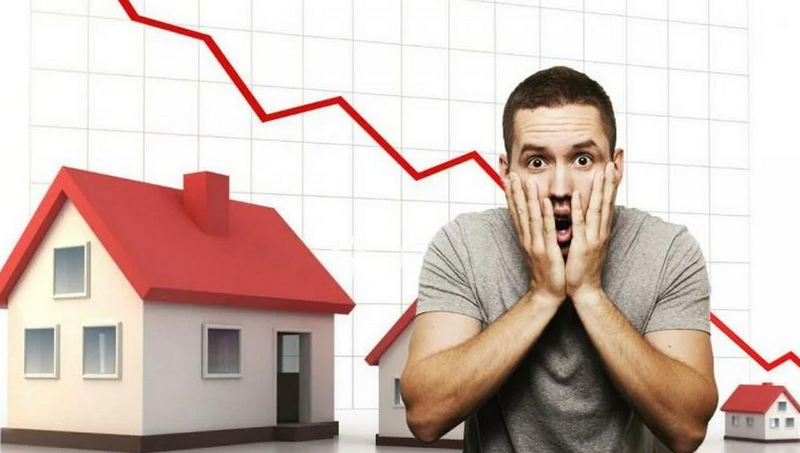 A man with a shocked expression stands in front of a declining graph with houses in the background.