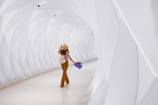 A person walks through a futuristic white tunnel, showcasing Binghatti Hills' unique architectural design.